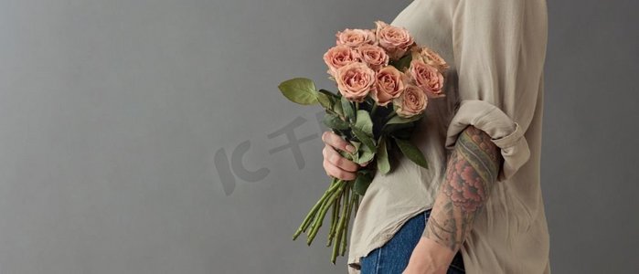 女人手里拿着花,手上有灰色的纹身.