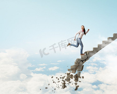 在阶梯上向上爬，克服挑战。一名年轻女子走上坍塌的楼梯，代表成功的概念
