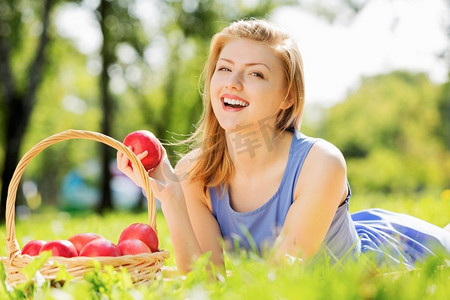 拿着苹果摄影照片_拿着苹果的女孩。夏日公园里的年轻美女带着苹果