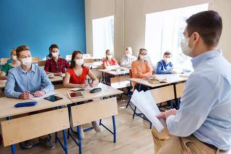 教育、流行病和健康概念—戴口罩的学生和学校的老师。一群戴着口罩的学生和老师在学校