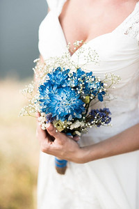 新娘手持印有蓝色花朵的结婚花束