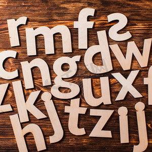 字母表中的大字母杂乱无章地散落在木质背景上。教育理念。零星大写字母