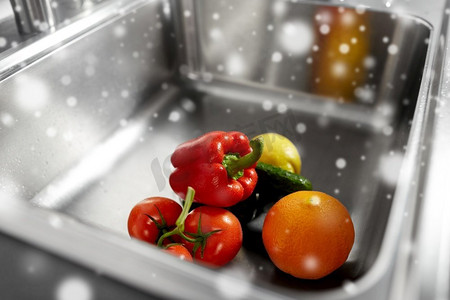 卫生，食品和安全概念—水果和蔬菜在不锈钢厨房水槽在冬季超过雪。厨房水槽中的水果和蔬菜