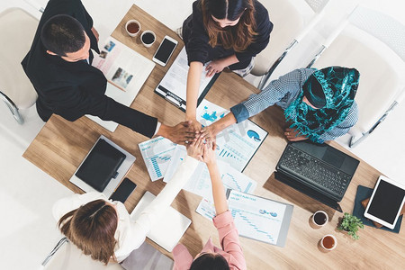 商人和女商人在多文化办公室的小组会议上携手合作,展示团队合作,支持