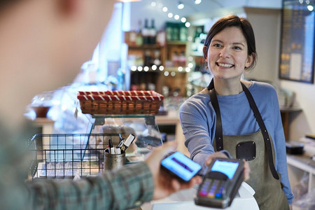 男性顾客在Delicatessen使用手机进行非接触式购物支付