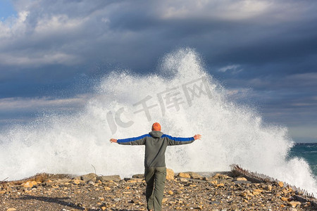 人站在码头上的大海与大浪打与飞溅在暴风雨天气