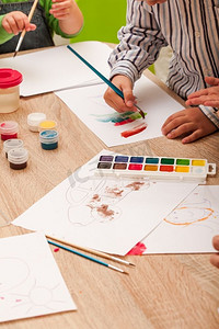 学画画摄影照片_孩子们在幼儿园里学习用毛笔和水彩画在纸上作画。孩子们在画画