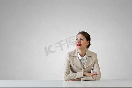 女商人坐在桌子上。愉快的有吸引力的女实业家坐在桌子在办公室