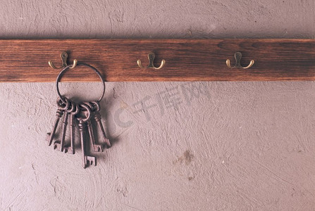 一串复古的金属钥匙环挂在钩子上，木质衣架上。挂钩上的钥匙