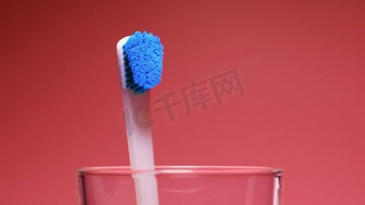 新的和旧的牙刷男性手替换磨损的牙刷在玻璃与新的在红色背景新老牙刷