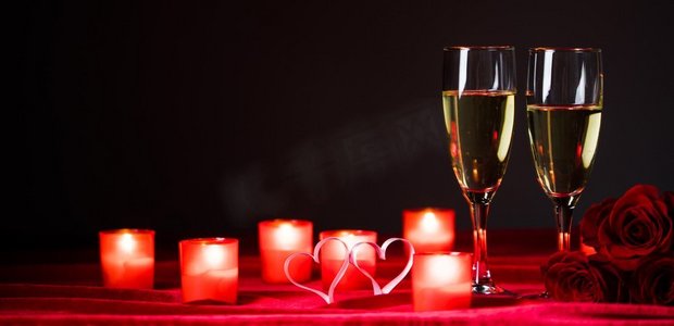 香槟和蜡烛。情人节庆祝活动，红丝绸上的香槟、蜡烛、玫瑰和红心