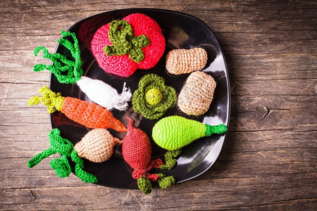 编织钩针摄影照片_在盘子上钩针编织蔬菜--儿童环保玩具和厨房装饰。钩针编织小蔬菜