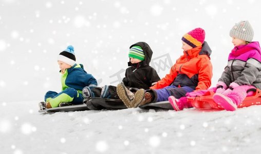 一群小孩子摄影照片_童年、雪橇和季节概念-一群快乐的小孩子在冬天滑雪橇。快乐的小孩子们在冬天滑雪橇