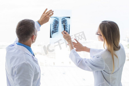 两名医生在诊所的窗口检查x光片。检查X光片的医生