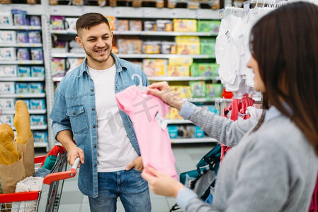 快乐夫妇购买儿童衣服在超市，家庭购物。顾客在商店，买家在市场，部门的商品为儿童