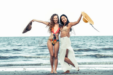 快乐的女人穿着比基尼跳舞在热带沙滩在暑假。旅行生活方式快乐的女人在夏天的沙滩上跳舞。