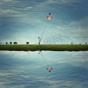 一个小男孩站在湖边的乡村草地上，手里拿着一些五颜六色的气球。生活的乐趣，乐趣和幸福。