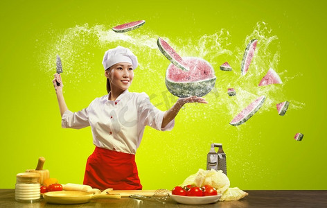 刀切水果摄影照片_亚洲女厨师用刀。亚洲女性厨师与刀切水果和蔬菜在空气中