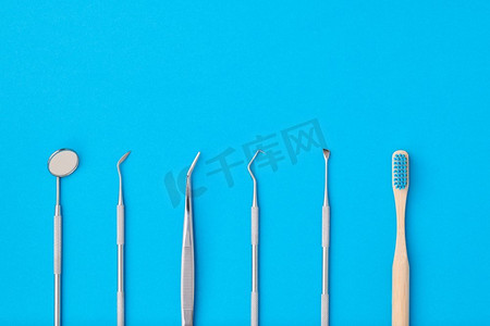 蓝色口腔健康摄影照片_牙科医生工具在蓝色背景顶视图复制空间平躺。牙齿护理，牙齿卫生和健康概念。 
