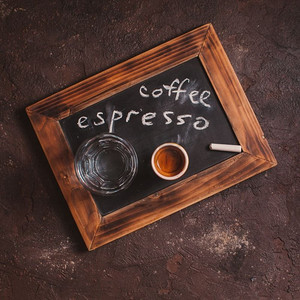 顶视图一杯咖啡和玻璃水在老学校石板与题字。为美食家准备的咖啡