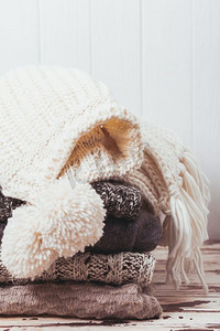 堆叠温暖的针织毛衣，围巾和帽子在白色和灰色的阴影。毛织品收藏