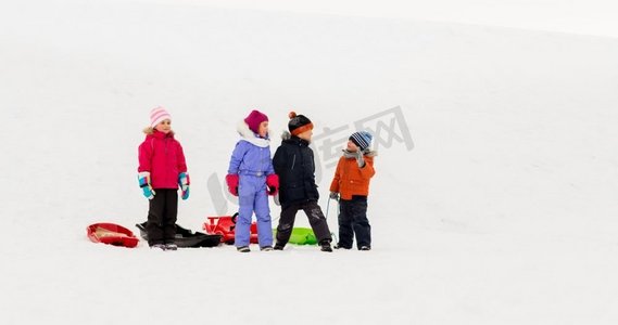 一群小孩子摄影照片_童年，雪橇和季节概念—一群快乐的小孩子在冬天雪橇。快乐的小孩子与雪橇在冬天