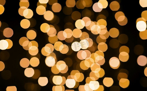 圣诞节和节日的概念-模糊的金色灯光在黑色背景上摇摆。模糊的金色波克灯