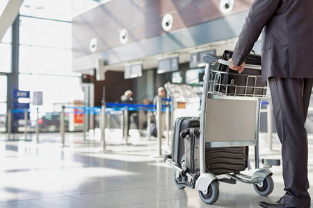 成熟的商人推行李车检查在机场