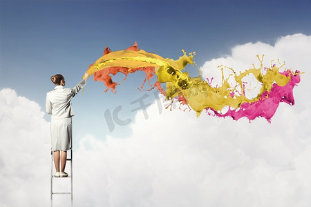 年轻女子画水花。站在梯子上画画的年轻女子用手指飞溅