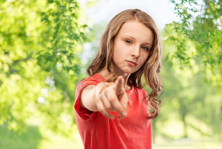 和人的概念-在绿色自然背景下,身穿红色 t 恤,长发的少女用手指指着你