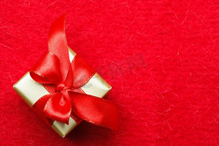 节日，礼物，圣诞节的概念。小的金色盒子与礼品系在红色背景装饰弓与复制空间