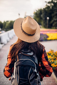 有背包的女性徒步旅行者在旅游城镇，背面视图。年轻女子的夏季徒步旅行，徒步旅行冒险