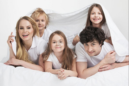 微笑的家人在床上。微笑的家庭与三个孩子在床上醒来