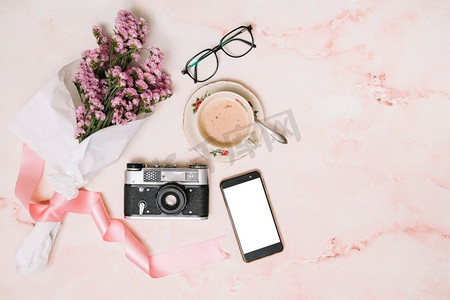 咖啡甜点摄影照片_鲜花花束与智能手机咖啡杯。漂亮的照片。鲜花花束与智能手机咖啡杯