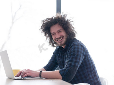 从上面摄影照片_一个年轻人一边喝着咖啡，一边在家里用笔记本电脑工作