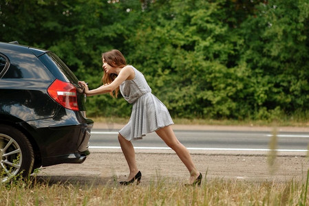 女人在路上推着坏车，抛锚了。汽车相撞或车辆发生紧急事故，高速公路引擎出现故障