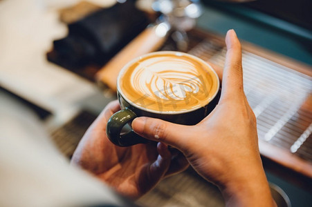 咖啡师制作拿铁艺术，拍摄焦点在一杯牛奶和咖啡，老式过滤器图像