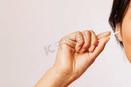 清洁工摄影照片_一名妇女用棉签擦耳朵。很漂亮的照片。一名妇女用棉签擦耳朵