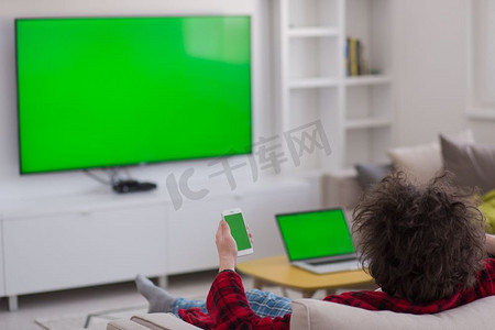 年轻英俊的男子穿着浴袍，在他的豪宅里享受着看电视的空闲时间