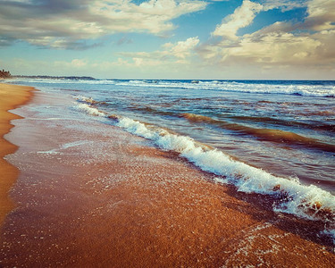 复古效果过滤了热带海滩上波浪涌动的潮人风格形象。希卡杜瓦，斯里兰卡。激荡在沙滩上的海浪