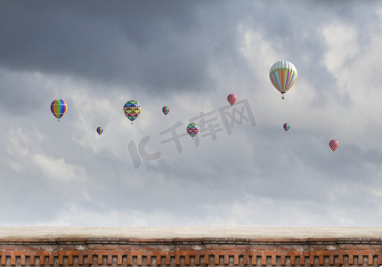 空中飞球摄影照片_会飞的浮空器。五颜六色的气球在灰色的天空中高高飘扬