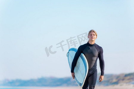 一名年轻的冲浪者在海滩上挥舞着冲浪板。准备好掀起波澜