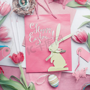 漂亮的粉彩复活节快乐卡片，上面有字母，郁金香花，鸡蛋和兔子装饰，俯视
