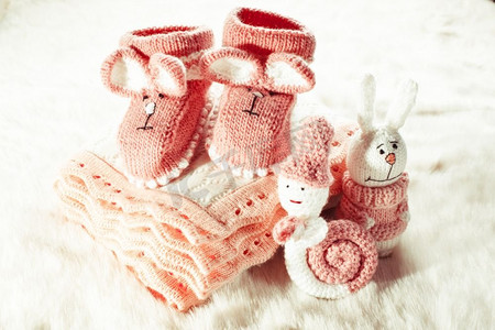 针织粉色婴儿靴子，玩具，小女孩的毯子。针织婴儿靴