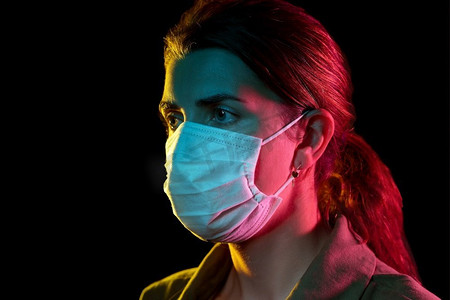 健康、安全和流行病概念-年轻女性在黑色背景下戴着防护性医用口罩。戴着防护医用口罩的年轻女子