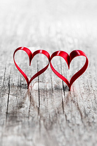 两个心形的丝带。两个红色丝带心脏在木backround，情人节概念