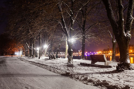 冷行人摄影照片_晚城白雪覆盖的堤岸。美丽的冬季风景。白雪覆盖的堤坝夜景