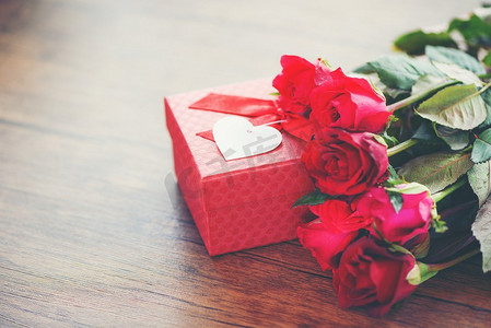 周年庆红金摄影照片_情人节礼物盒花爱概念/有丝带弓的红色礼物盒在木桌上的红玫瑰花质朴的背景色调葡萄酒 
