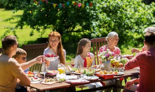 欢乐假期摄影照片_消闲、度假和人的概念—欢乐的家庭聚餐或夏季花园聚会。快乐的家庭有晚餐或夏季花园聚会