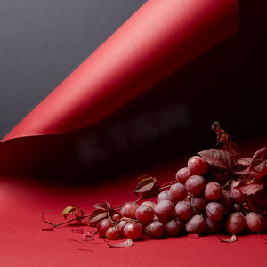 一串红葡萄叶的葡萄，红背景。成熟的新鲜红葡萄在红色背景